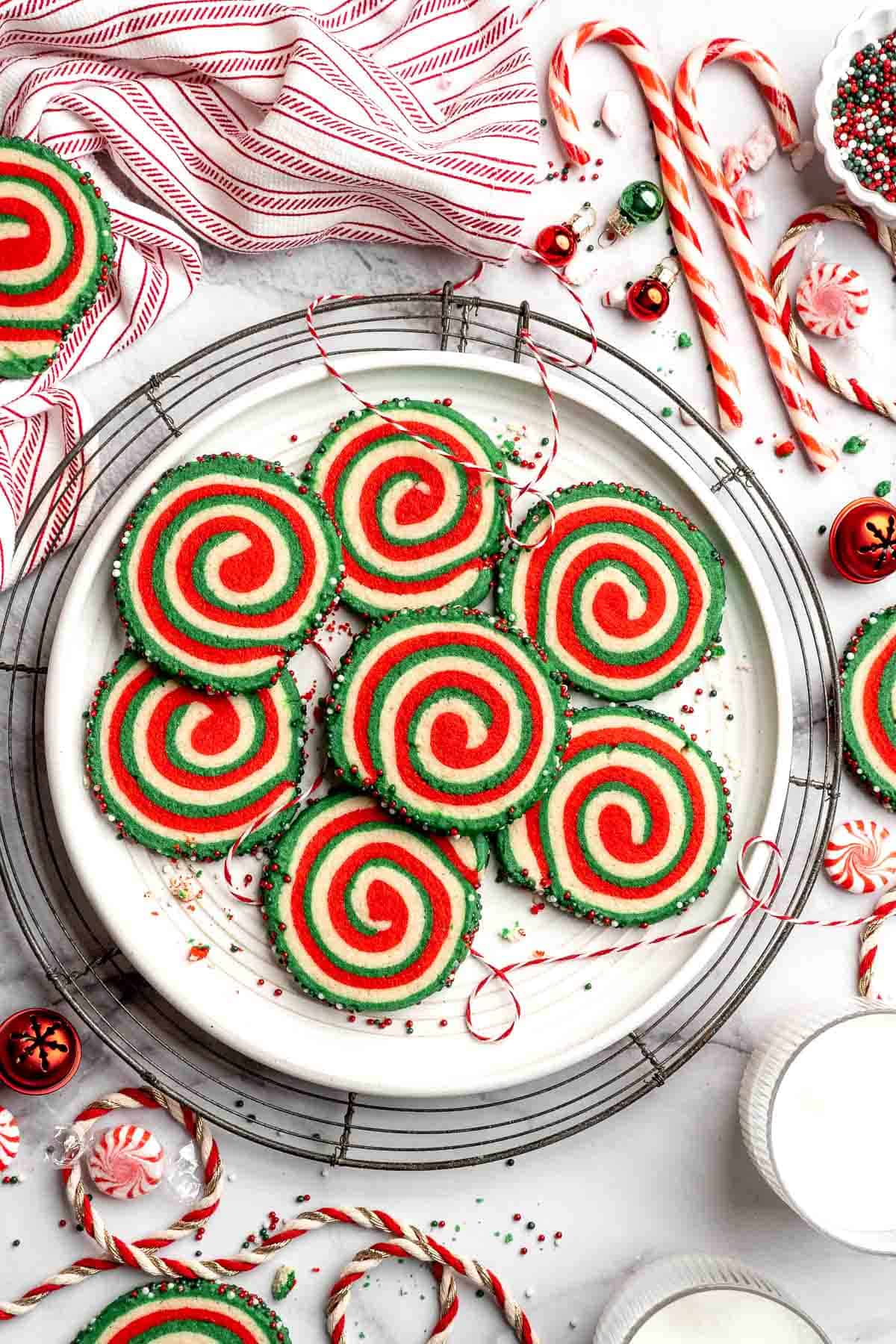 Peppermint pinwheel cookies with red, green, and white swirled dough rolled in festive sprinkles. A fun slice and bake Christmas cookie. | aheadofthyme.com