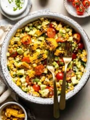Avocado corn salad with grilled corn, avocado, cherry tomatoes, cucumber, red onion, cilantro, and lime dressing.