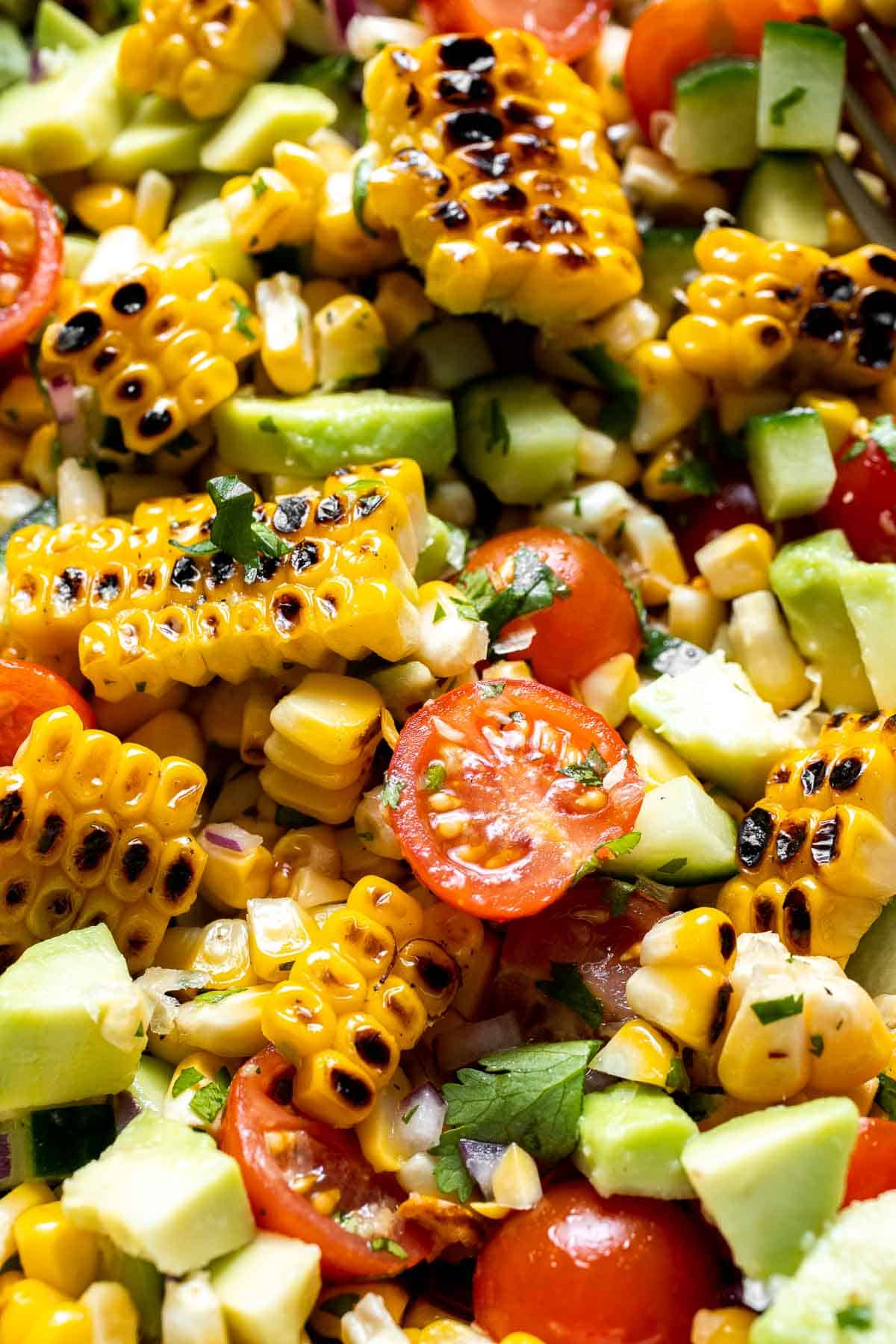 Close-up of avocado corn salad with grilled corn, avocado, cherry tomatoes, and cucumber.