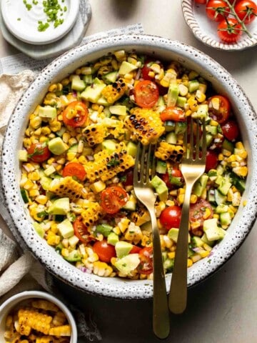 Avocado corn salad with grilled corn, avocado, cherry tomatoes, cucumber, red onion, cilantro, and lime dressing.
