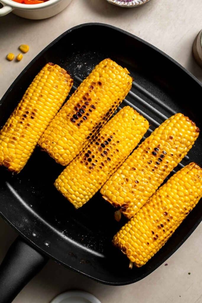 Fresh corn cooking in a grill pan for avocado corn salad.