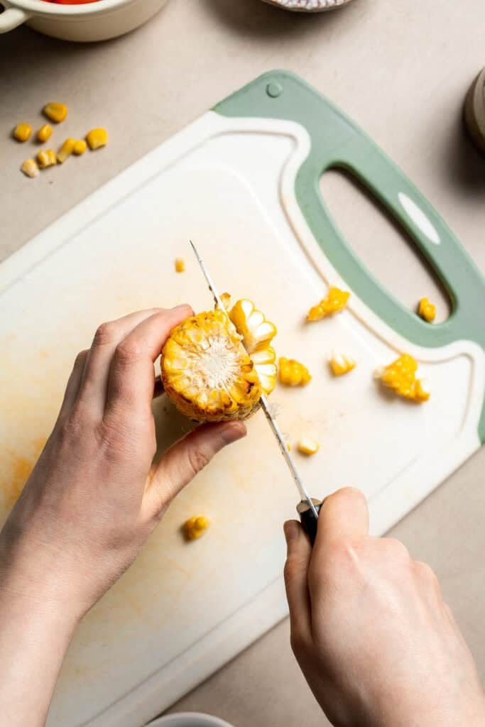 Removing corn kernels from a cooked ear of corn.