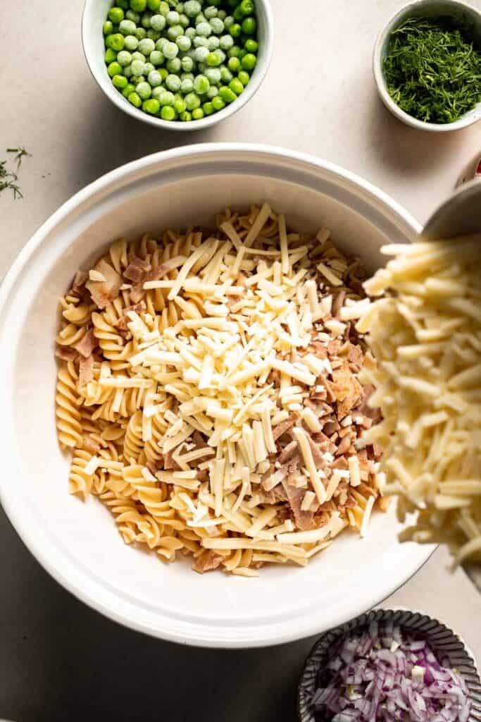 Shredded cheddar cheese added to pasta and bacon.