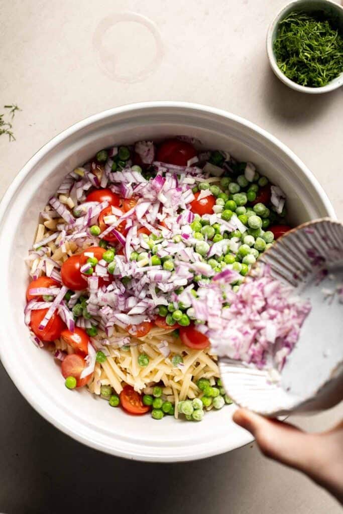 Red onion and peas added to the pasta salad mixture.