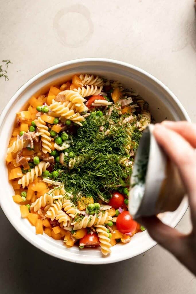 Fresh herbs being added to bacon ranch pasta salad.
