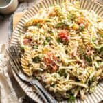 Bacon ranch pasta salad with crispy bacon, cheddar cheese, peas, tomatoes, and creamy ranch dressing.