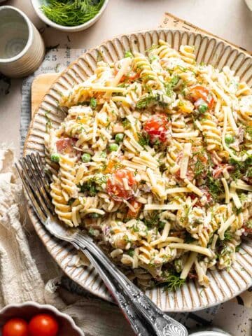 Bacon ranch pasta salad with crispy bacon, cheddar cheese, peas, tomatoes, and creamy ranch dressing.