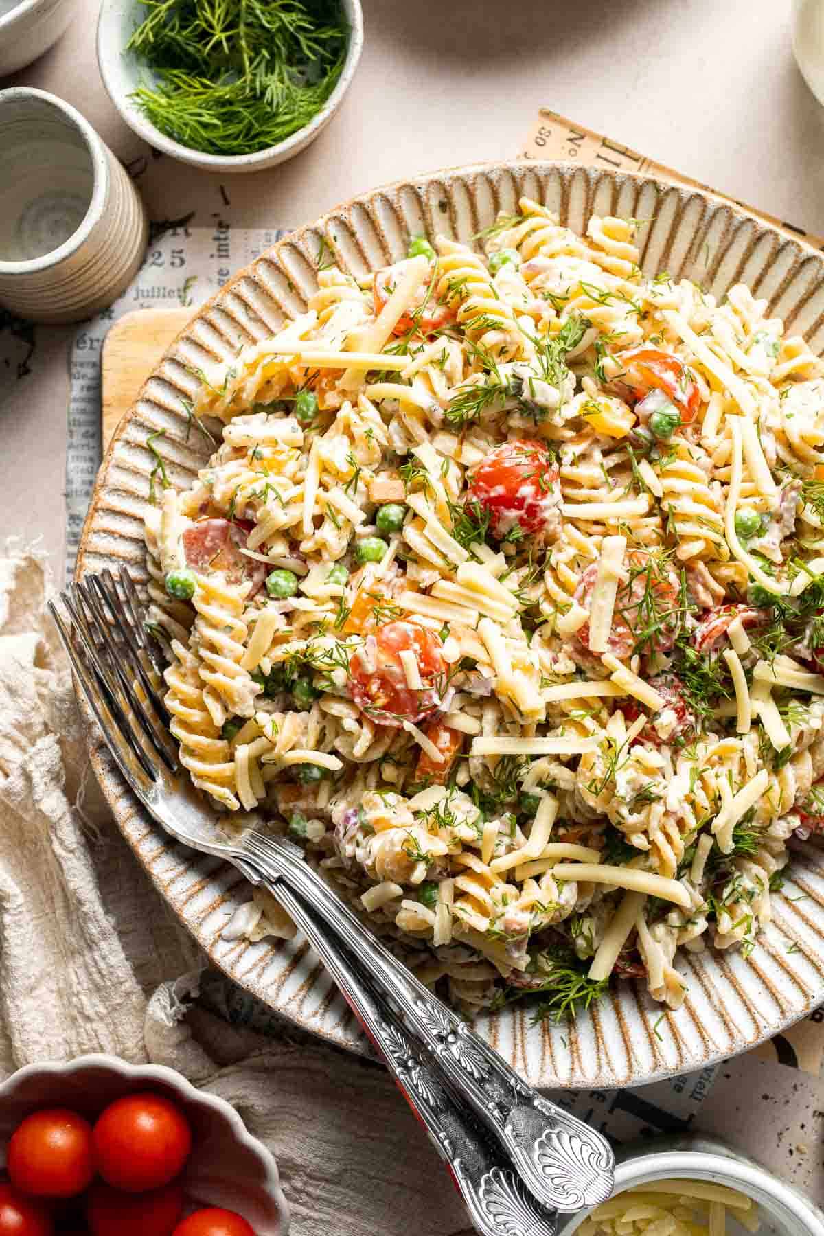 Bacon ranch pasta salad with crispy bacon, cheddar cheese, peas, tomatoes, and creamy ranch dressing.