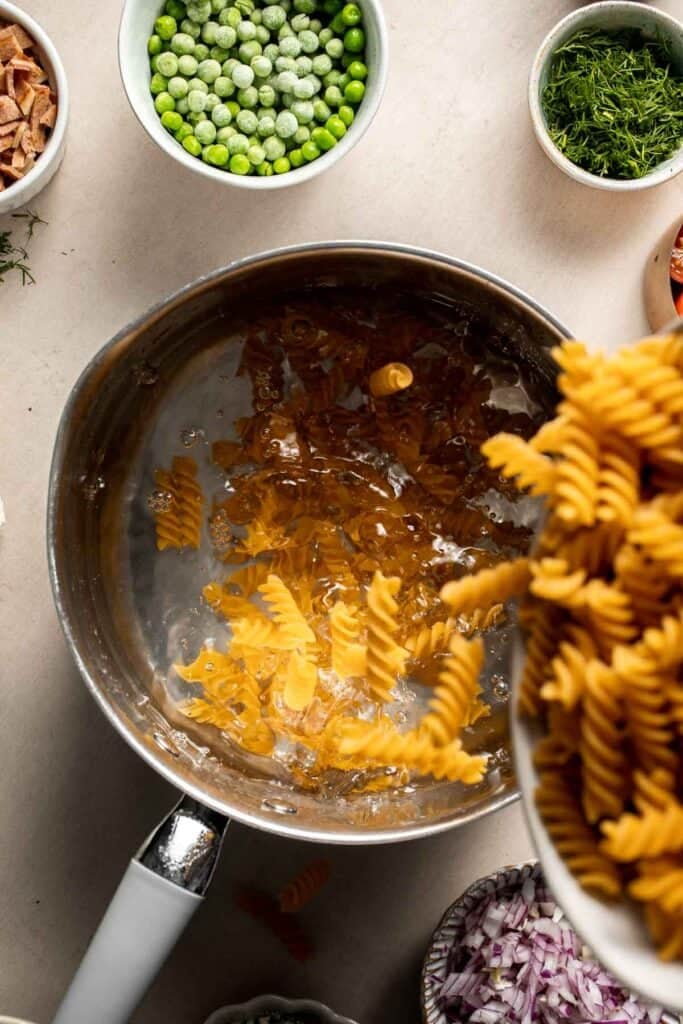 Rotini pasta being added to a pot of boiling water.