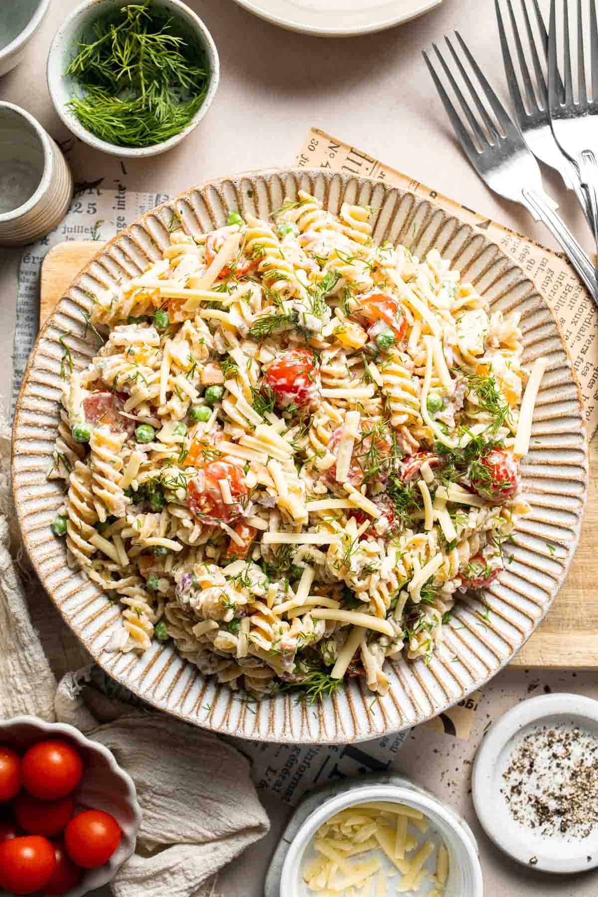 Bacon ranch pasta salad served on a platter with fresh herbs and vegetables.