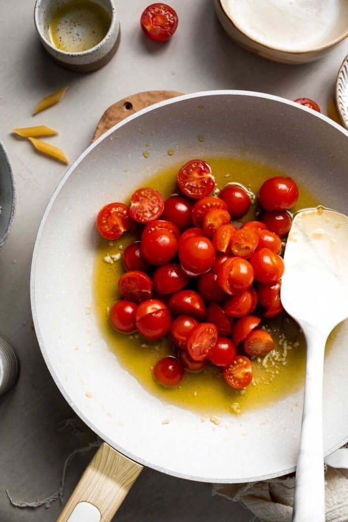 Fresh cherry tomatoes cooking in a skillet and beginning to soften.