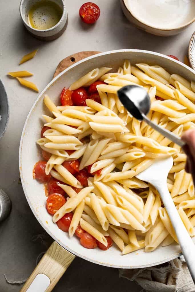 Tomato mozzarella pasta mixed together in a skillet.