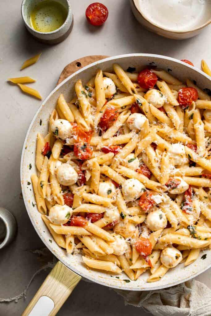 Easy tomato mozzarella pasta ready to serve with fresh basil and Parmesan cheese.