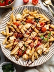 Caprese pasta with fresh mozzarella, cherry tomatoes, basil, Parmesan cheese, and balsamic glaze. Easy tomato mozzarella pasta recipe.