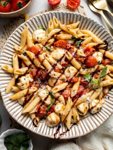 Caprese pasta with fresh mozzarella, cherry tomatoes, basil, Parmesan cheese, and balsamic glaze. Easy tomato mozzarella pasta recipe.