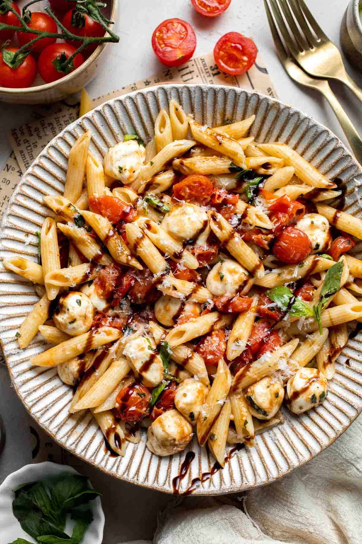 Caprese pasta with fresh mozzarella, cherry tomatoes, basil, Parmesan cheese, and balsamic glaze. Easy tomato mozzarella pasta recipe.