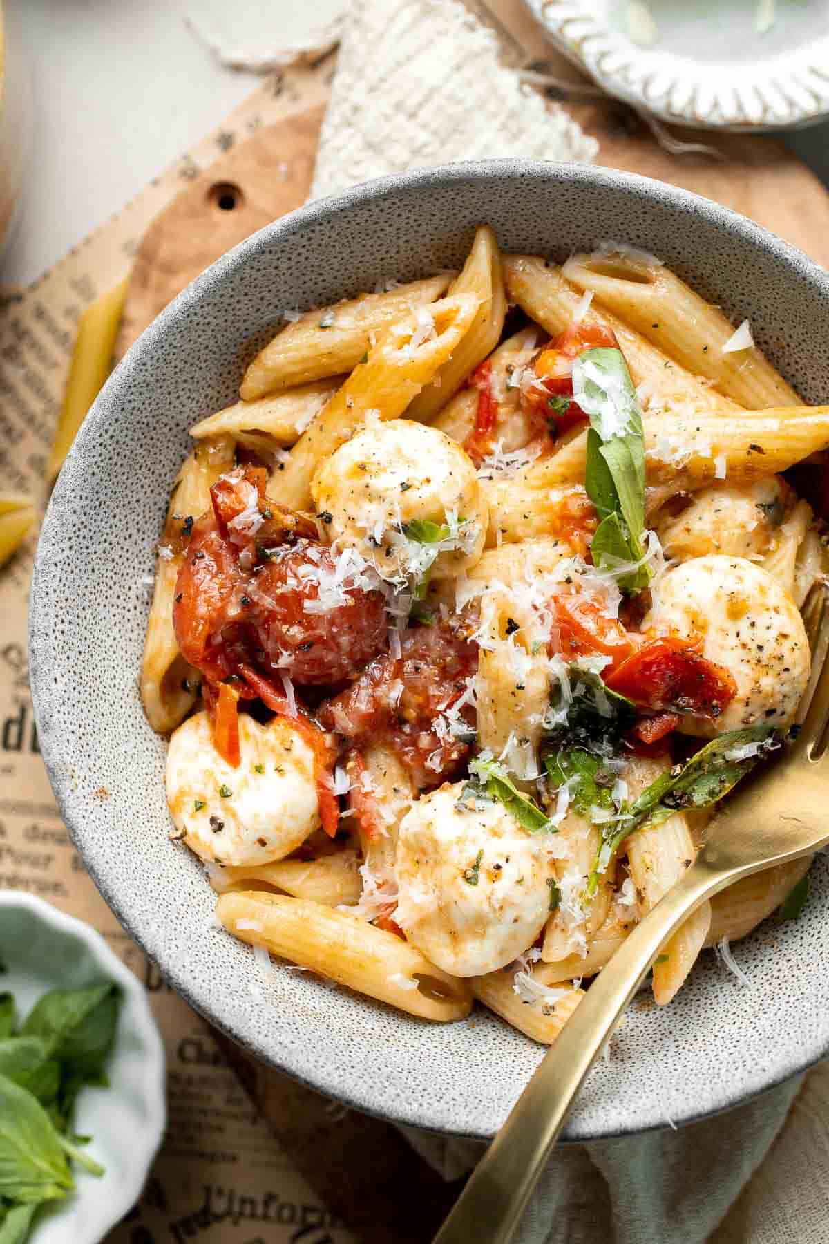 Close-up of Caprese pasta drizzled with balsamic glaze and topped with fresh mozzarella and basil.