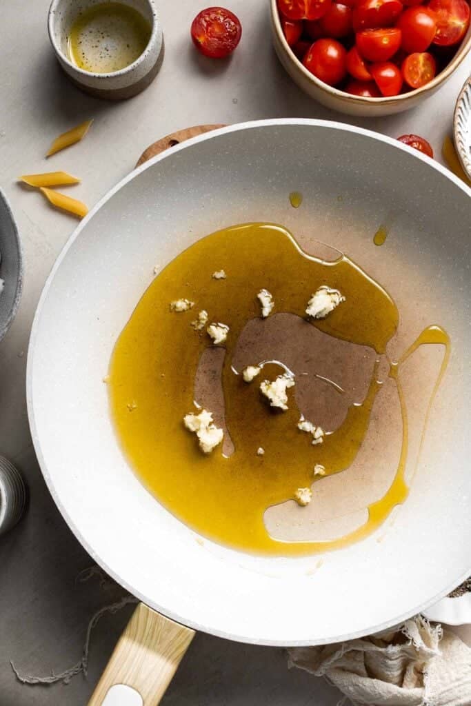 Olive oil and minced garlic heating in a large skillet.