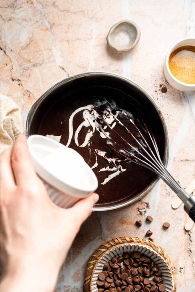 Heavy cream being added to the warm chocolate mixture.