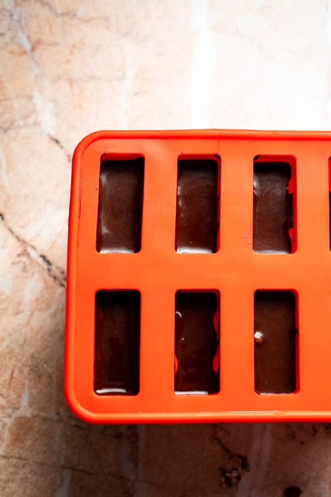 Chocolate fudgesicle mixture poured into popsicle molds.