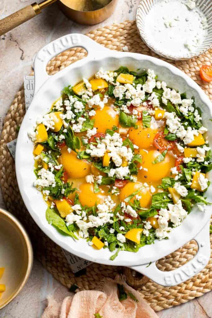 Crumbled feta cheese sprinkled over baked eggs and vegetables.