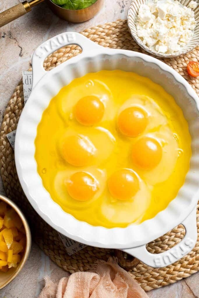 Eggs cracked into a casserole dish and spaced evenly apart.