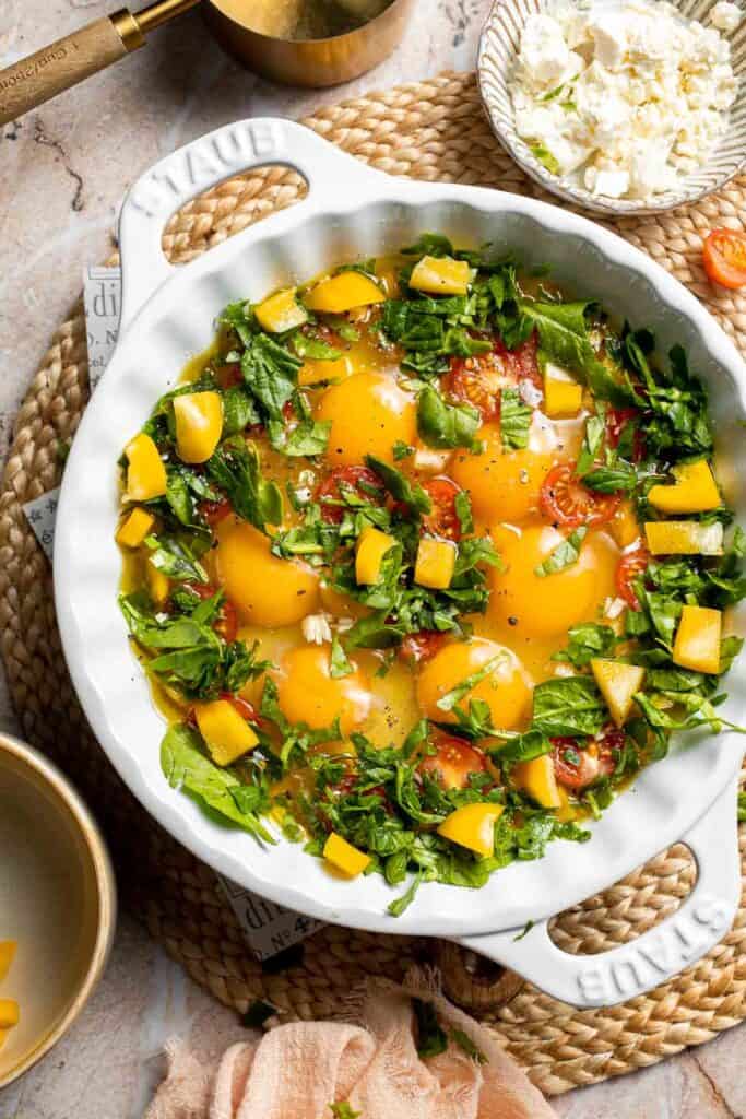 Cherry tomatoes, bell pepper, spinach, and garlic added around the eggs.
