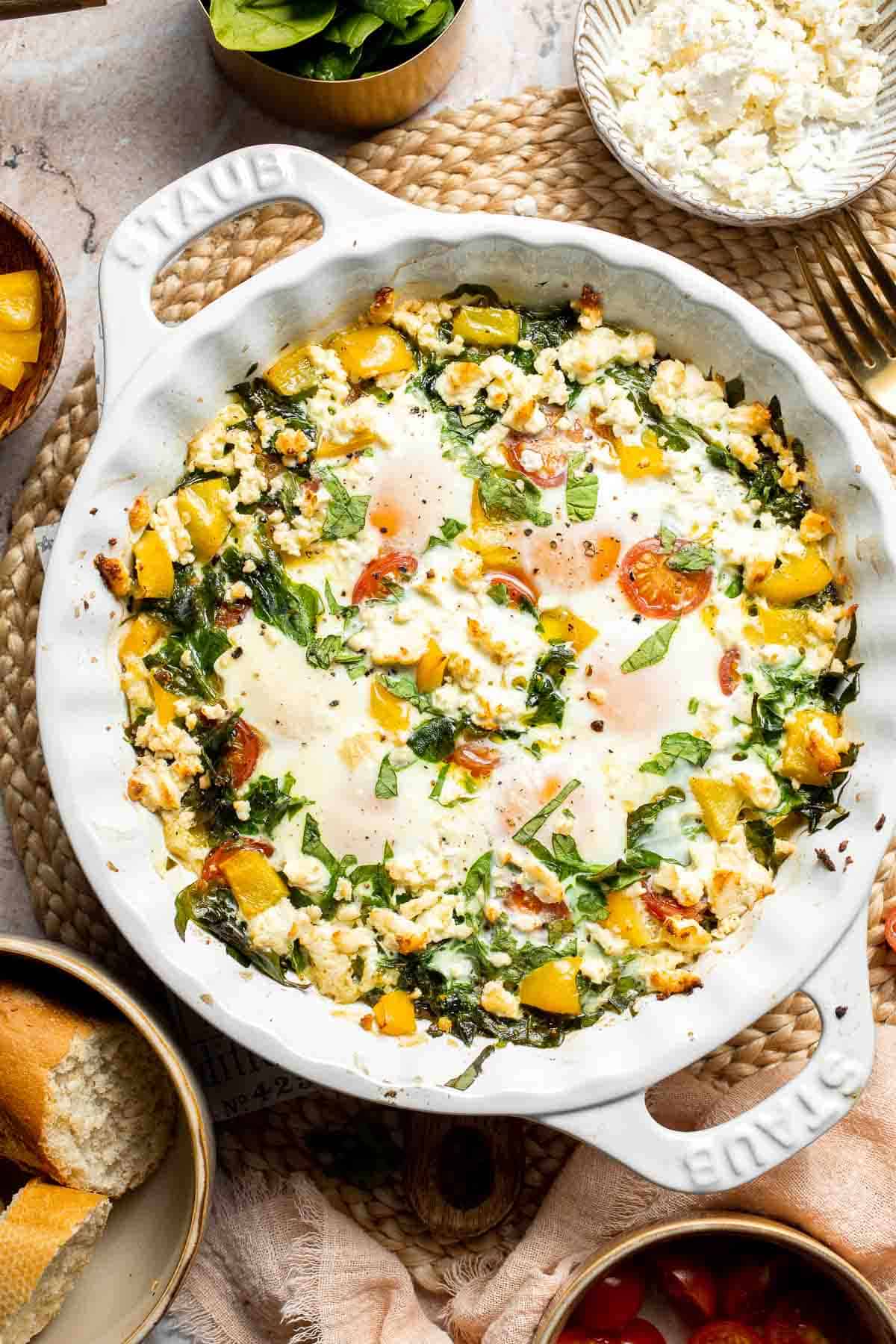 Mediterranean baked eggs with feta and tomatoes, spinach, bell peppers, and baked eggs in a one-pan breakfast dish.
