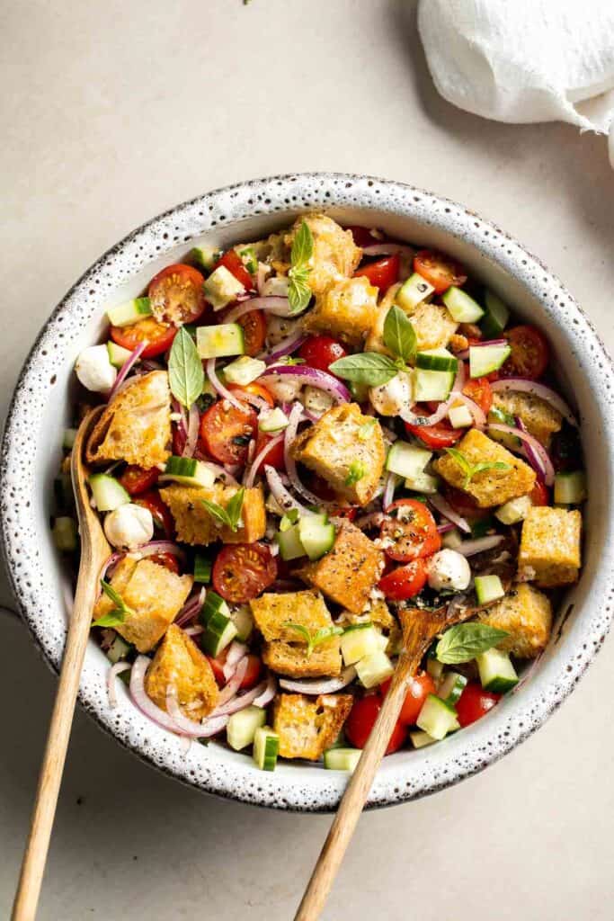 Panzanella salad topped with fresh basil, red onion, tomatoes, cucumber, and mozzarella