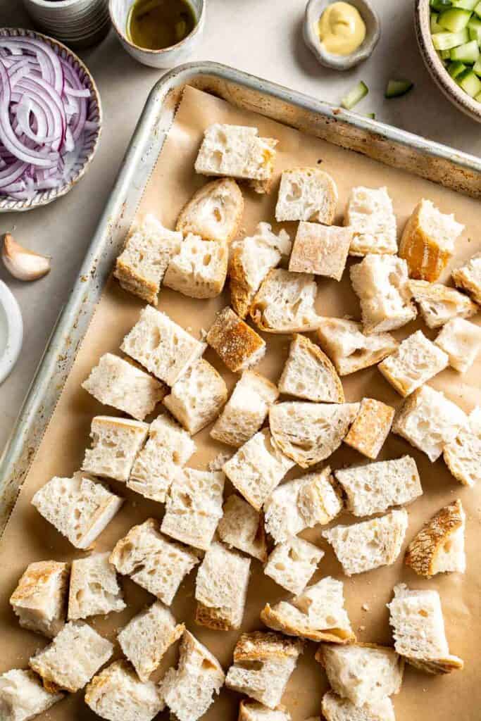Bread cubes spread on a baking sheet before toasting for panzanella salad