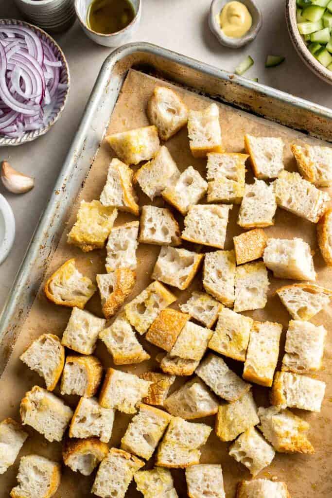 Bread cubes tossed with olive oil on a baking sheet for panzanella salad