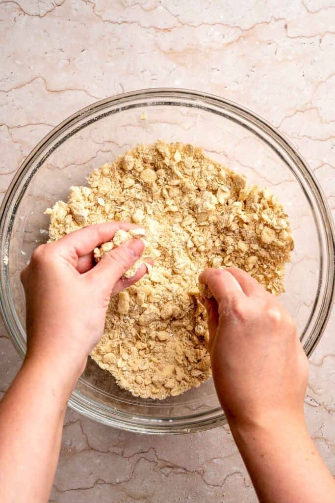 Cutting cold butter into the crumble topping mixture.