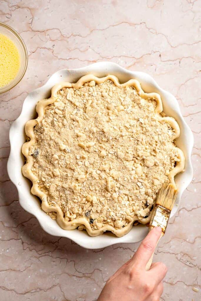 Blueberry crumble pie brushed with egg wash and ready to bake.