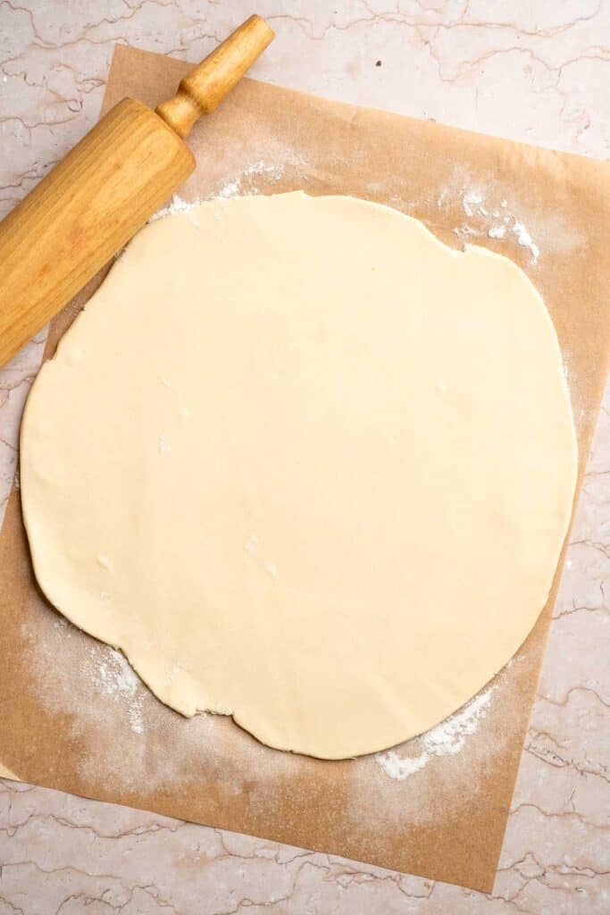 Pie dough rolled into a large circle on a lightly floured surface.