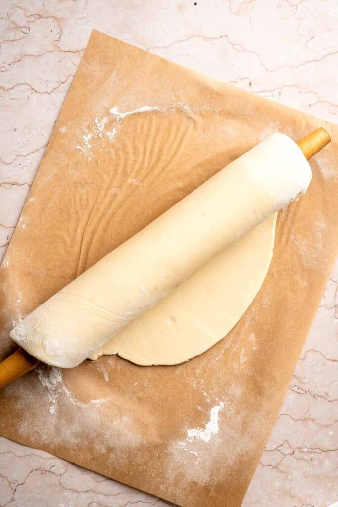 Rolling out homemade pie dough with a rolling pin.