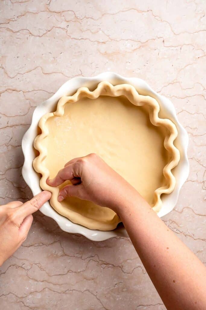 Crimping the edges of the blueberry pie crust.