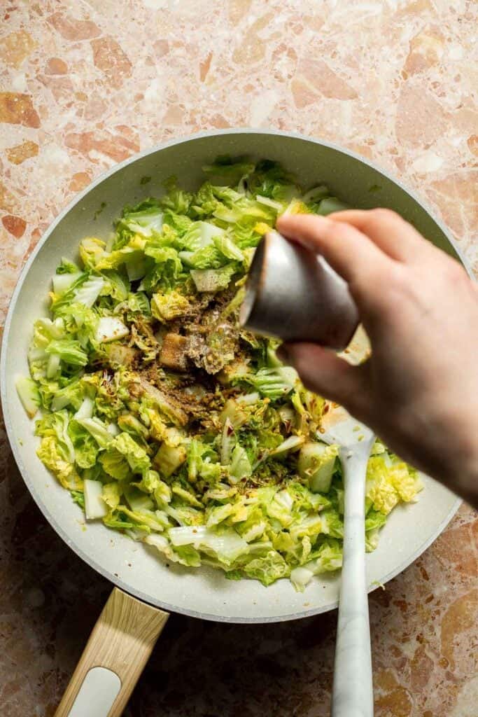 Rice vinegar being added to cabbage while making Chinese Cabbage Stir Fry.