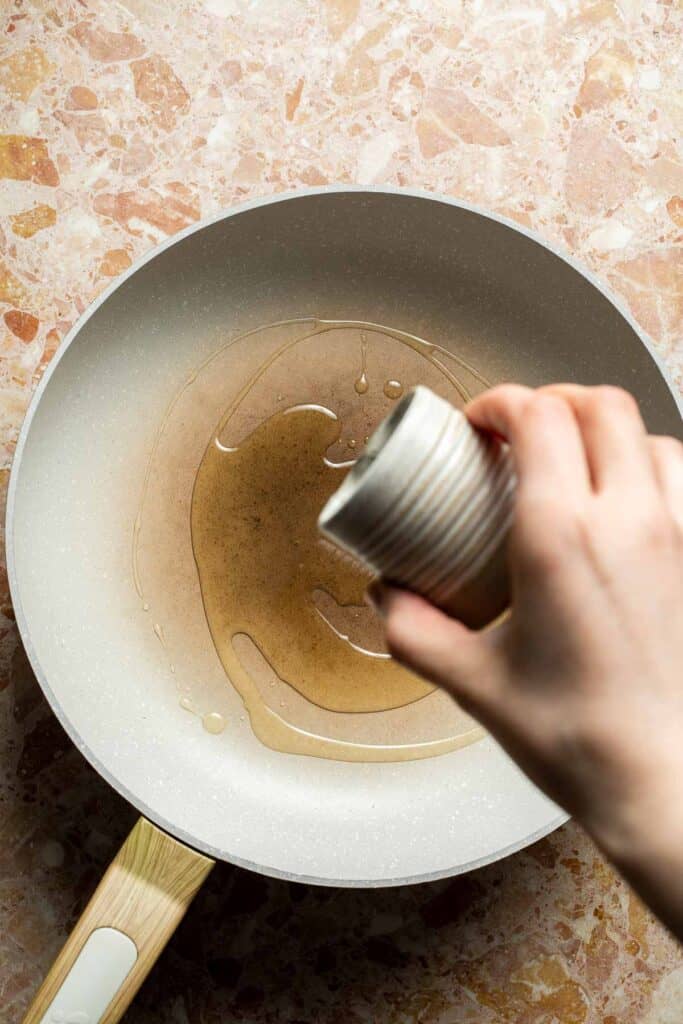 Sesame oil being poured into a skillet for Chinese Cabbage Stir Fry.