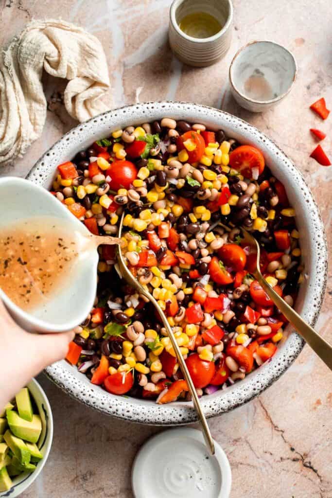 Pouring the homemade lime dressing over Cowboy Caviar in a large mixing bowl.