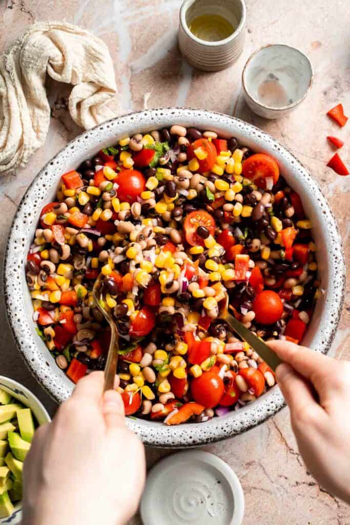 Tossing Cowboy Caviar with the fresh lime dressing until evenly coated.