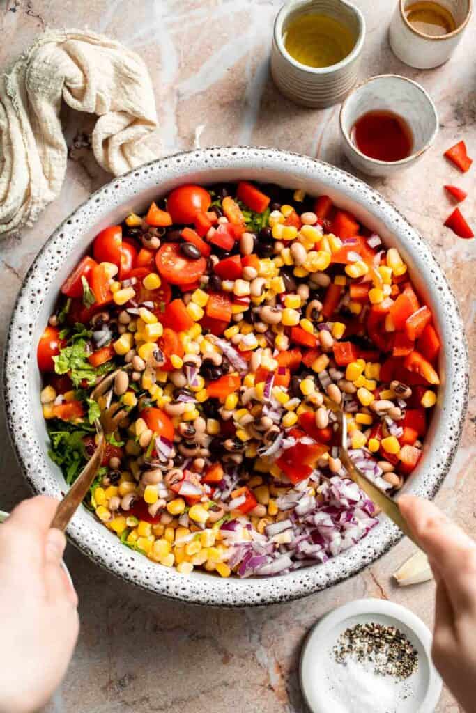 Mixing together the beans, corn, tomatoes, peppers, onion, and cilantro for Cowboy Caviar.