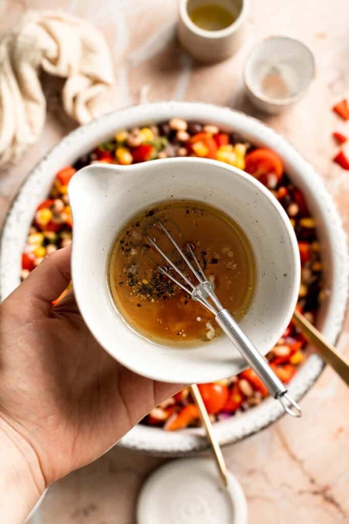 Whisking together the homemade lime dressing for Cowboy Caviar in a small bowl.