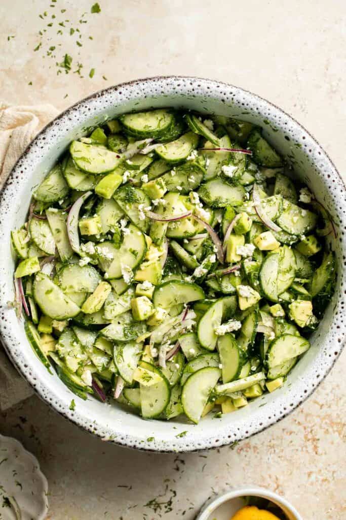 Fresh cucumber feta salad with avocado, red onion, dill, and parsley.