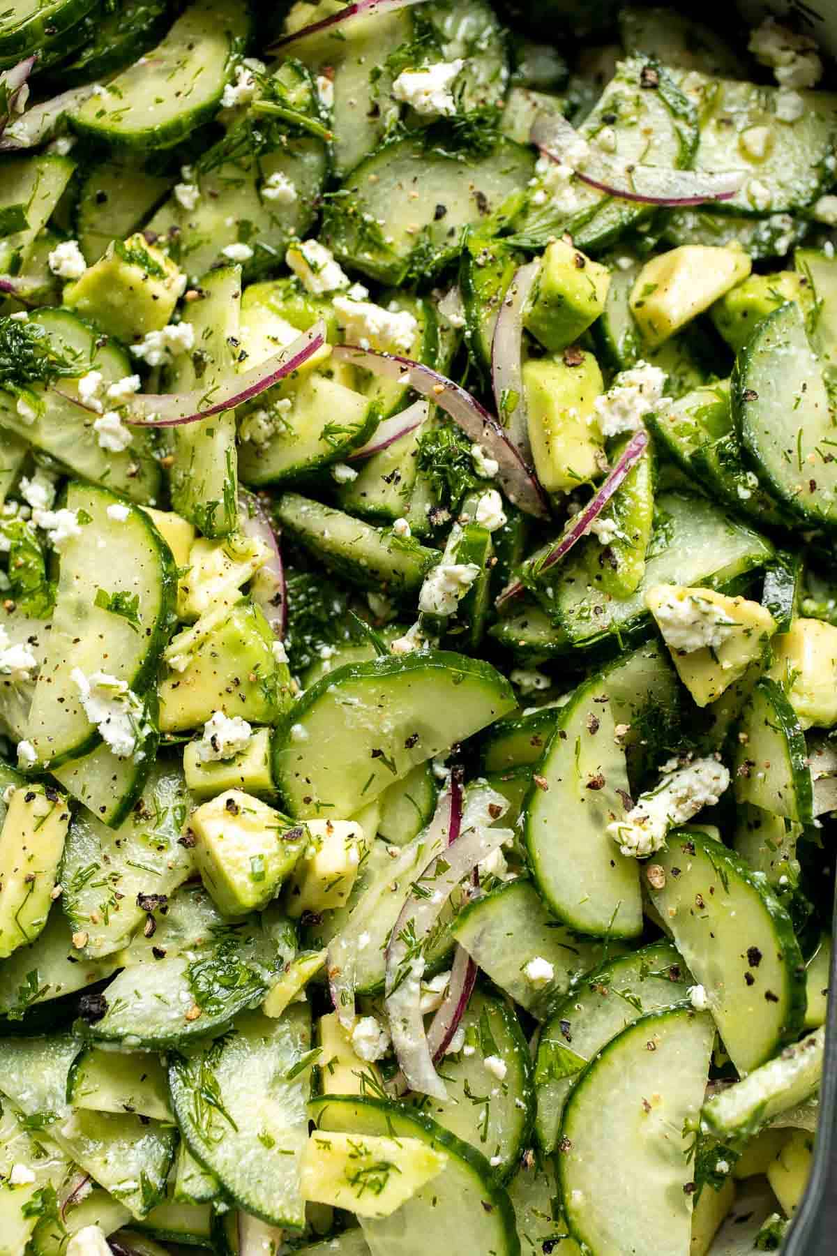 Close up of cucumber feta salad with avocado, red onion, fresh dill, and crumbled feta cheese.