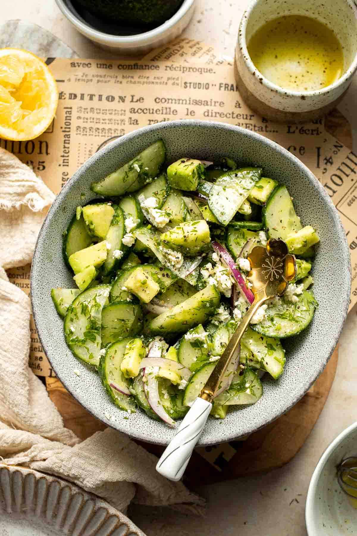 Cucumber feta salad served in a bowl with avocado, fresh herbs, and lemon dressing.