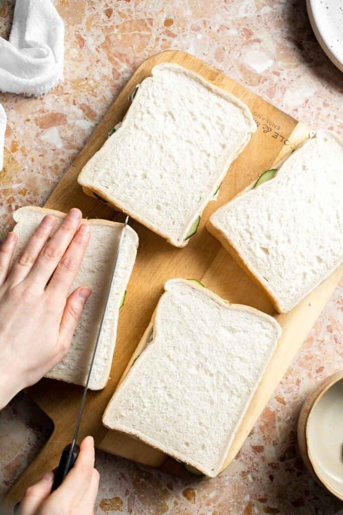 Trimming the crusts from Cucumber Tea Sandwiches with a sharp knife.