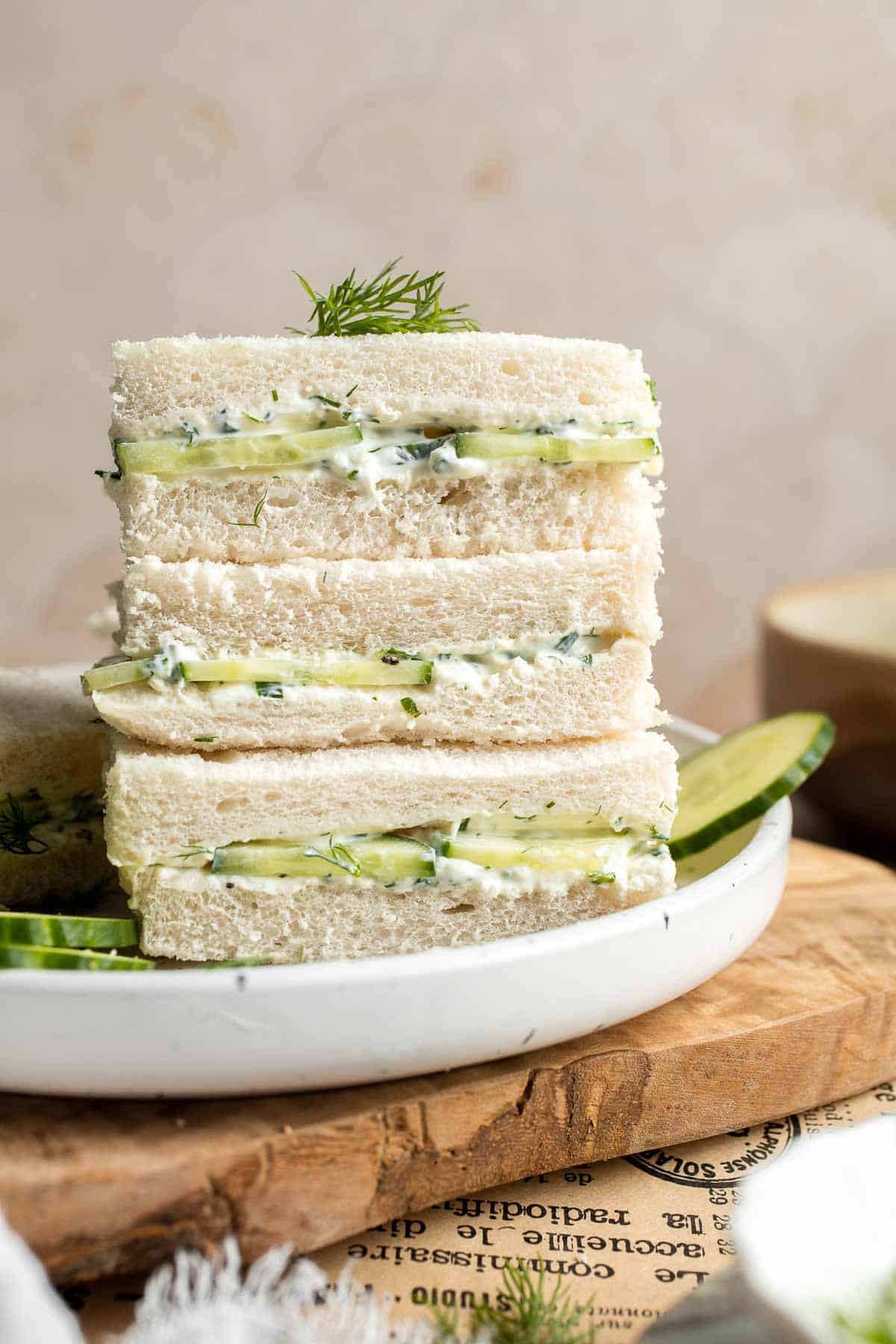 Stack of Cucumber Tea Sandwiches filled with thinly sliced cucumber and creamy herb spread, garnished with fresh dill.