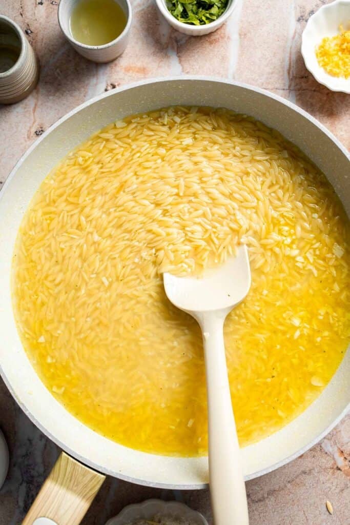 Stirring orzo and bringing to a boil.