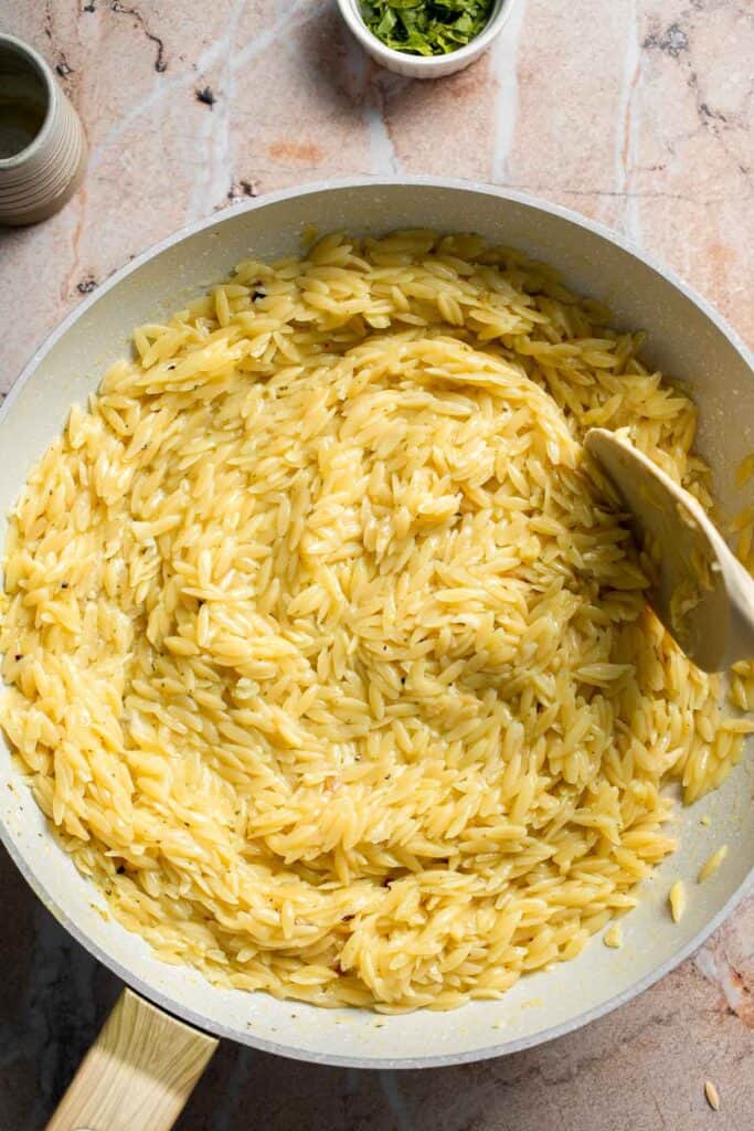 Stirring butter, Parmesan, and lemon into creamy Lemon Orzo.
