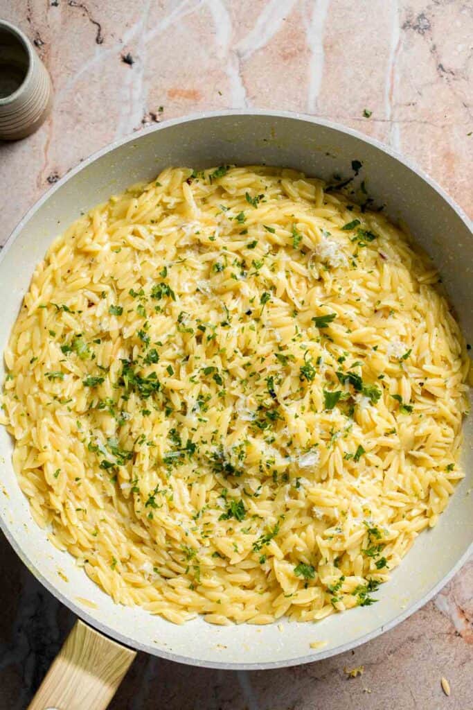 Finished Lemon Orzo garnished with fresh parsley in a skillet.